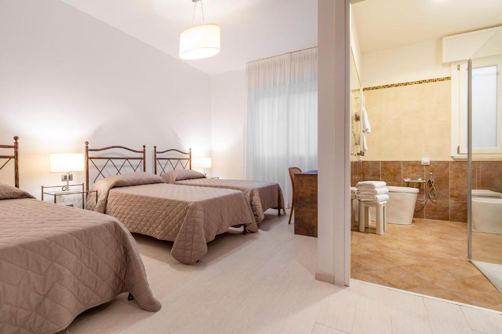 Cet appartement comprend une chambre avec deux lits et une salle de bains pourvue d'une baignoire. dans l'établissement Hotel Sorriso, sur le Lido de Venise