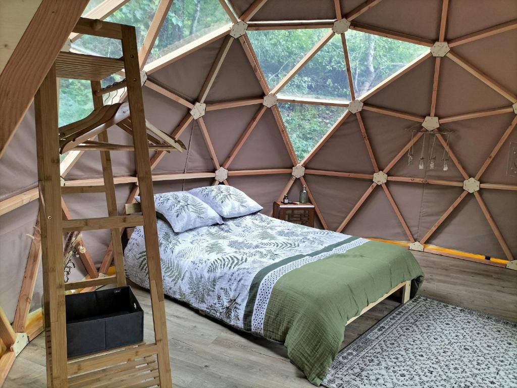- une chambre avec un lit et une échelle dans une yourte dans l'établissement Petite Fugue, à Cransac