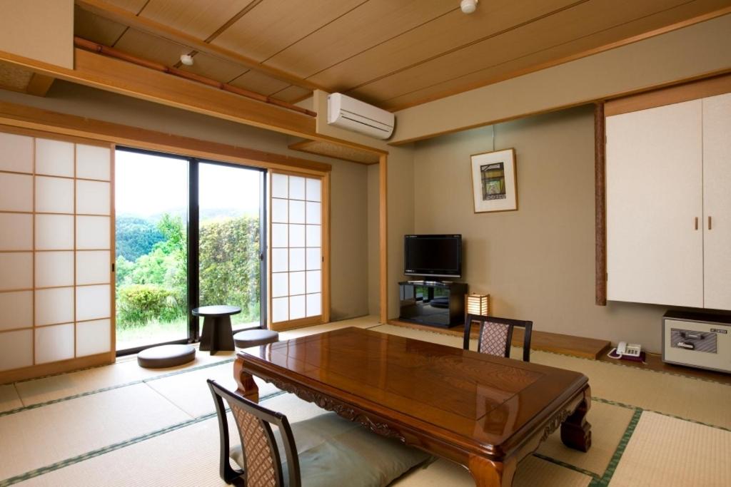 un salon avec une table et une grande fenêtre dans l'établissement Shorenji Lake Hotel, à Nabari