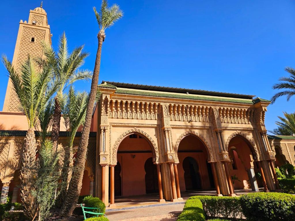 un bâtiment avec un palmier et une tour d'horloge dans l'établissement Riad yazuinaa, à Marrakech