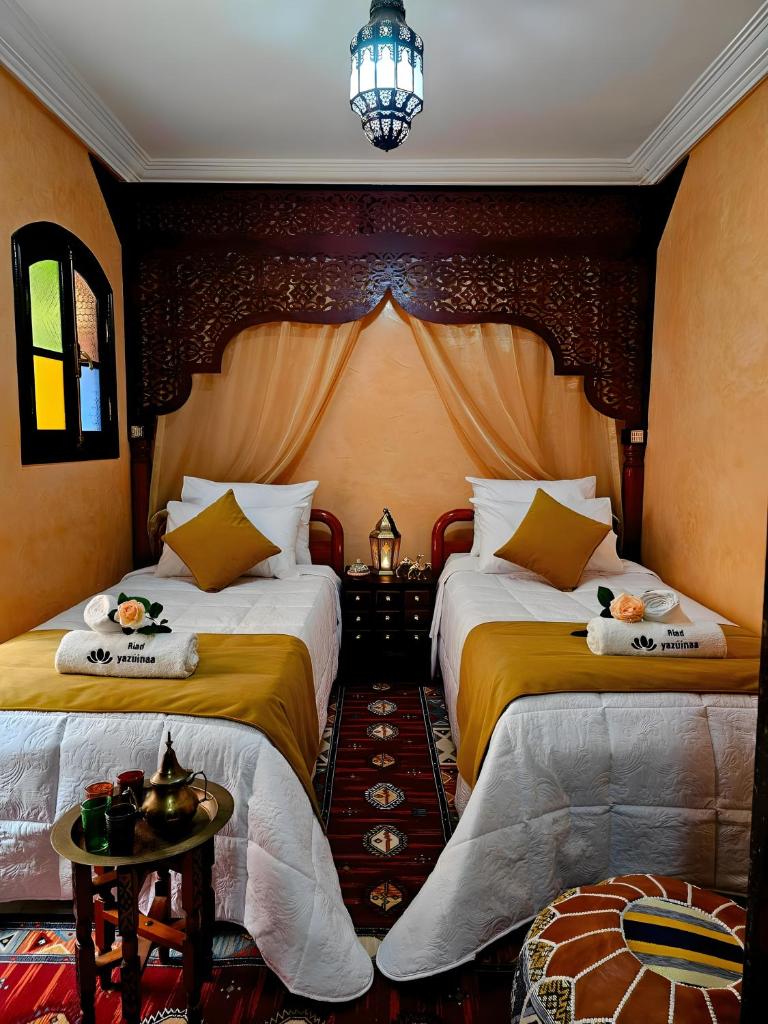 une chambre d'hôtel avec deux lits et une table dans l'établissement Riad yazuinaa, à Marrakech