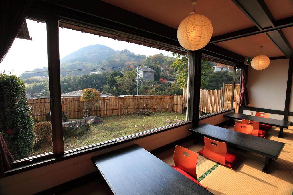une pièce avec une table et des chaises et une grande fenêtre dans l'établissement Kokoronodoka, à Kawazu