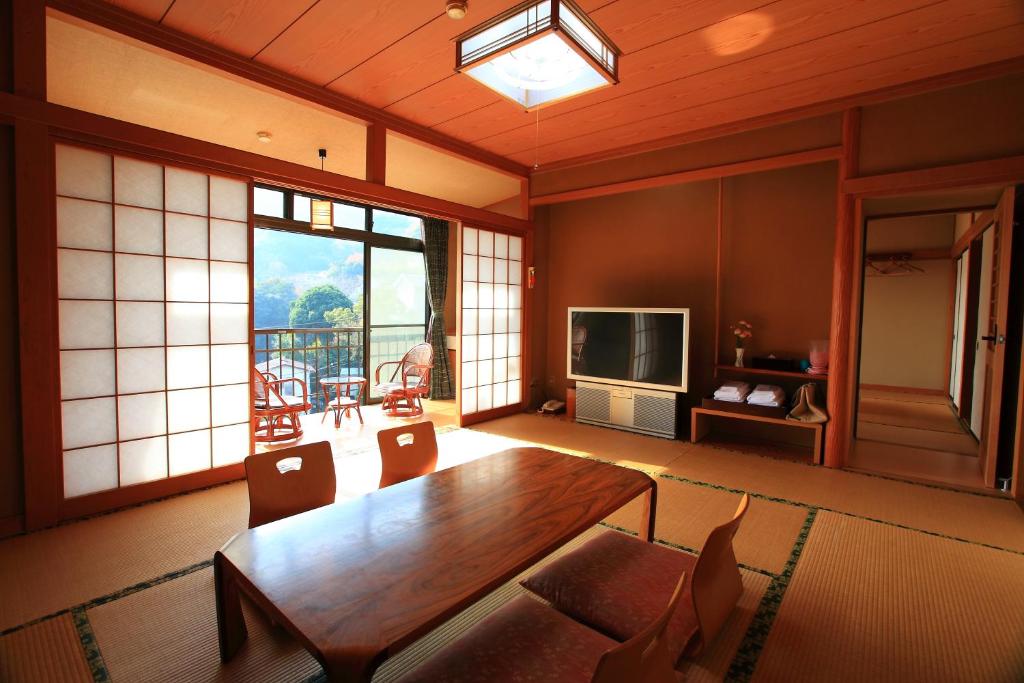 un salon avec une table en bois et une télévision dans l'établissement Kokoronodoka, à Kawazu 37 autres photos