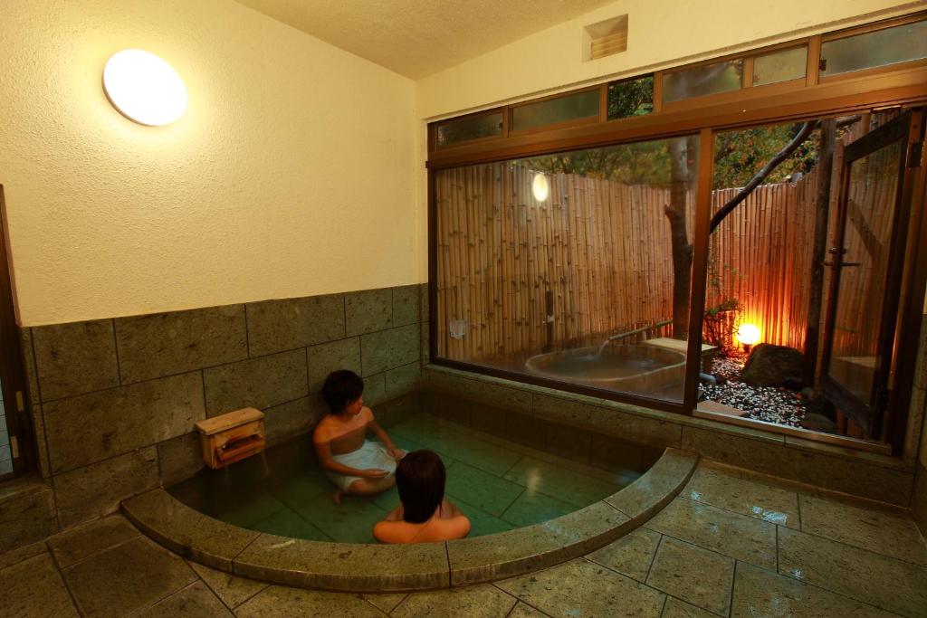 2 enfants assis dans un bain à remous dans une pièce dans l'établissement Kokoronodoka, à Kawazu