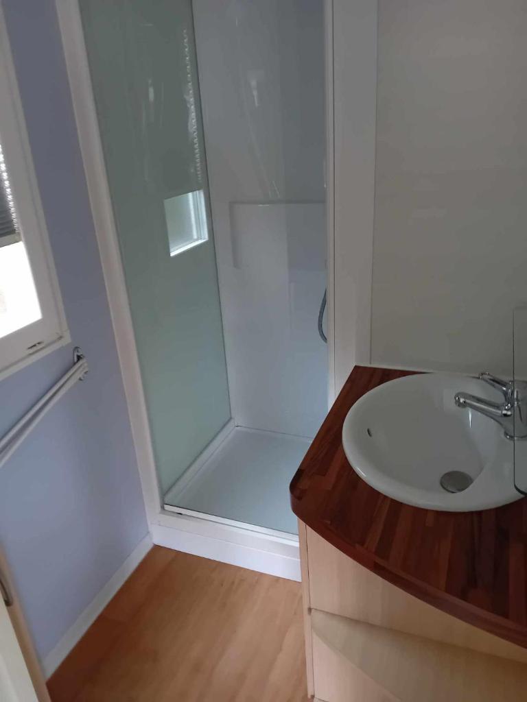 une salle de bain blanche avec une douche et un lavabo dans l'établissement mobilhome 5 couchages, à Nages
