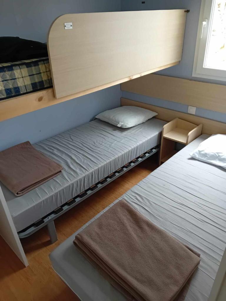 deux lits dans une petite pièce avec un miroir dans l'établissement mobilhome 5 couchages, à Nages 6 autres photos