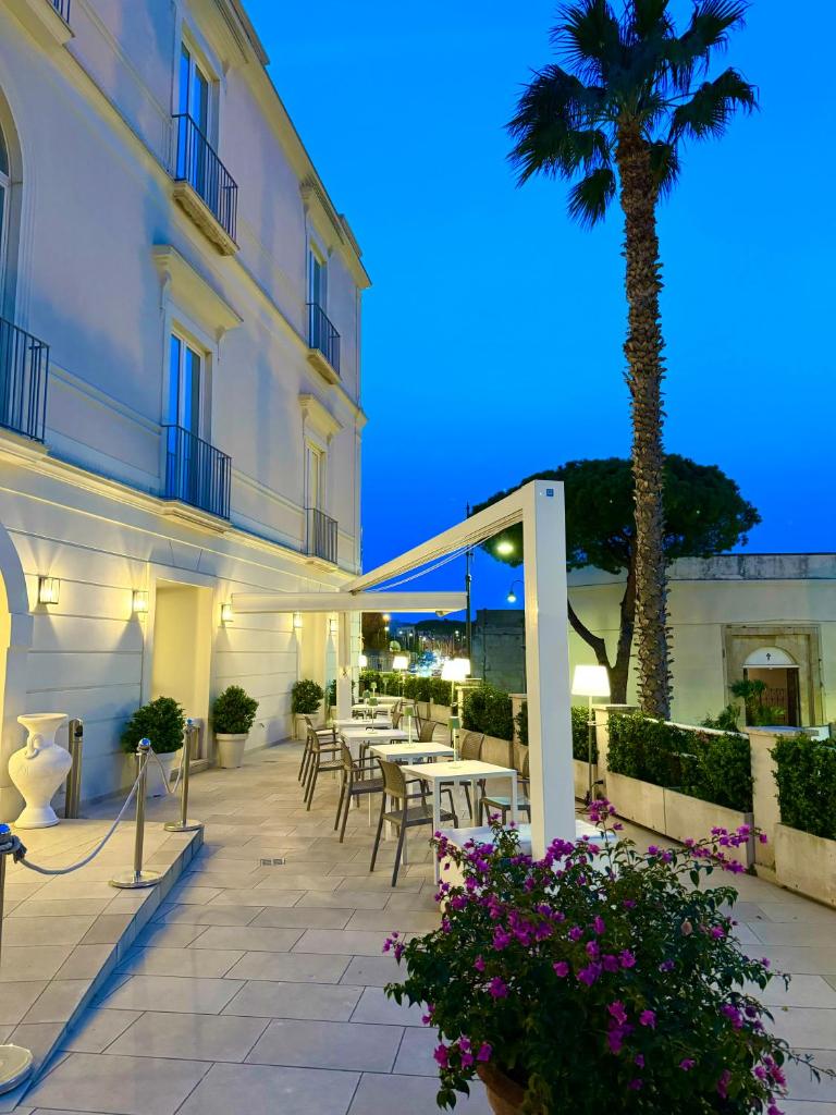 un patio avec tables et chaises et un palmier dans l'établissement Hotel Gajeta, à Gaète