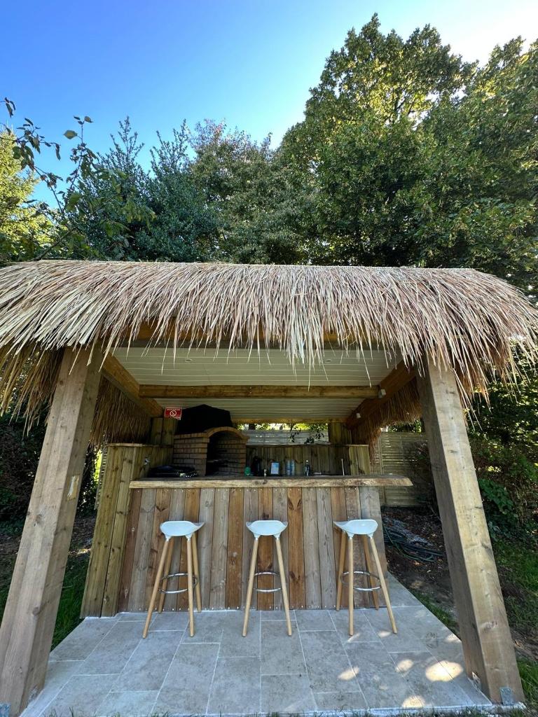 une cabane avec deux tabourets et un toit de chaume dans l'établissement Gîte Corrézien 3 pers. Piscine chauffée, à Chamboulive