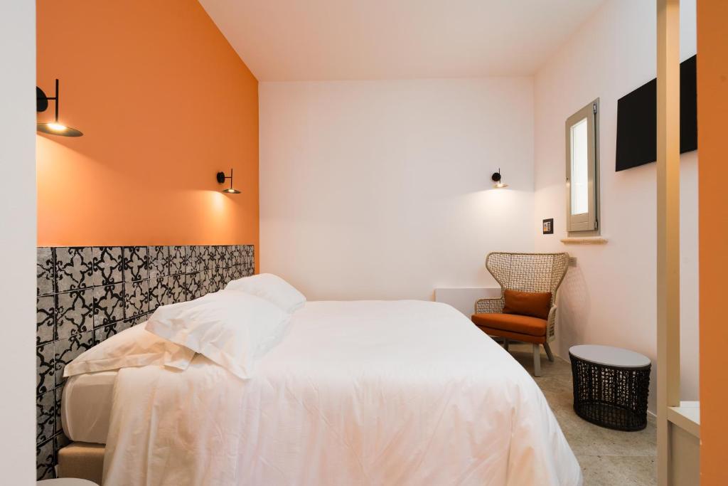 une chambre avec un lit blanc et un mur orange dans l'établissement Volito Rural Experience, à Patù
