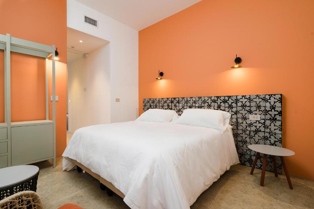 une chambre avec un grand lit avec un mur orange dans l'établissement Volito Rural Experience, à Patù