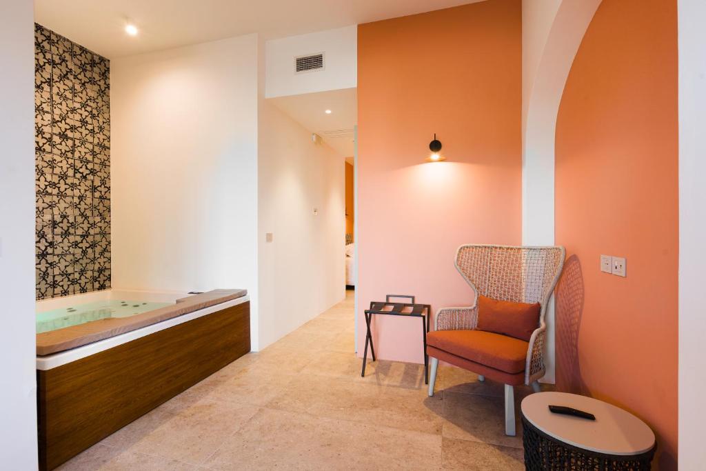 une salle de bain avec une baignoire, une chaise et une table dans l'établissement Volito Rural Experience, à Patù