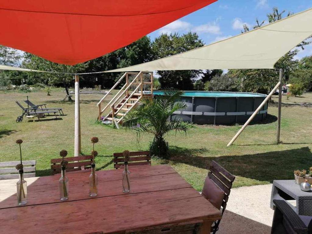 une table en bois avec des chaises et un parapluie rouge dans l'établissement Pays de Joie - Caravan La Bohème, à Saint-Macoux