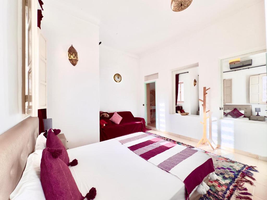 - une chambre avec un lit blanc et un canapé rouge dans l'établissement Riad La Rose Des Sables, à Marrakech