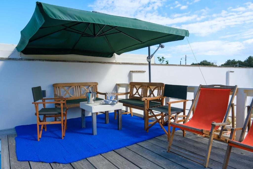une table et des chaises sous un parasol vert sur une terrasse dans l'établissement Villa Oasi al mare near the sea with pool - Happy Rentals, à Melendugno