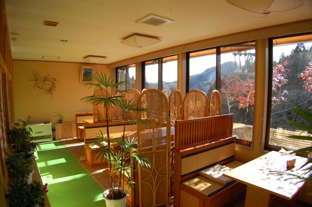 une pièce avec des tables et des chaises et une grande fenêtre dans l'établissement Sawatari Onsen Miyataya Ryokan, à Nakanojo