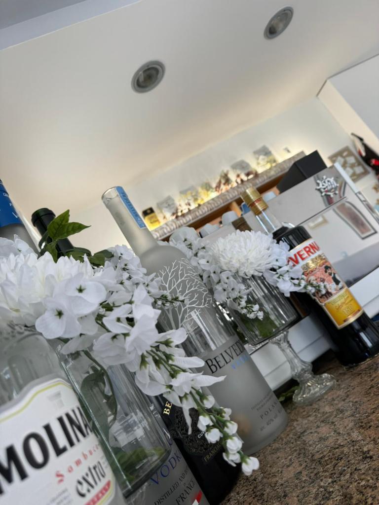 - un comptoir de cuisine avec des bouteilles de vin et des fleurs dans l'établissement Hotel Vera, à Cesenatico