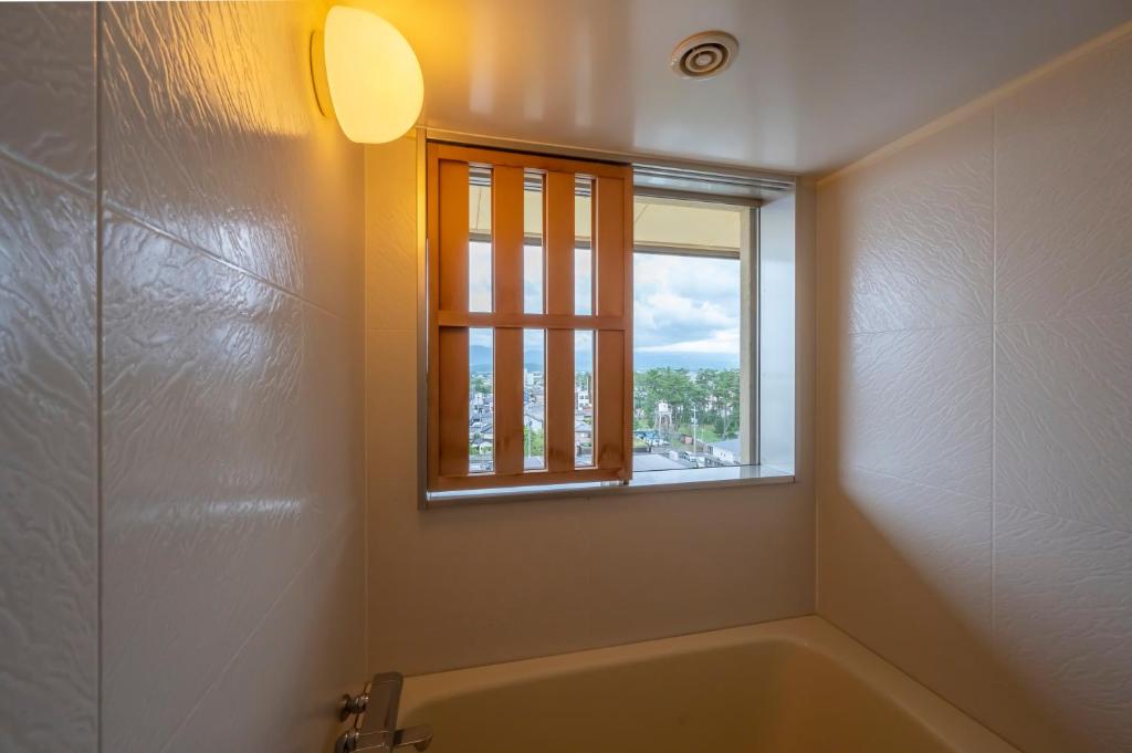 une salle de bain avec une baignoire et une fenêtre dans l'établissement Kaike Tsuruya, à Yonago