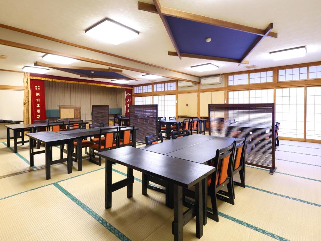 une salle à manger avec tables, chaises et fenêtres dans l'établissement 信州安曇野穂高温泉郷　旅館　山のたこ平, à Azumino