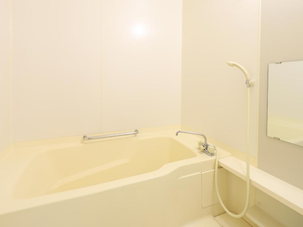 une baignoire blanche dans une salle de bain avec un miroir dans l'établissement 信州安曇野穂高温泉郷　旅館　山のたこ平, à Azumino