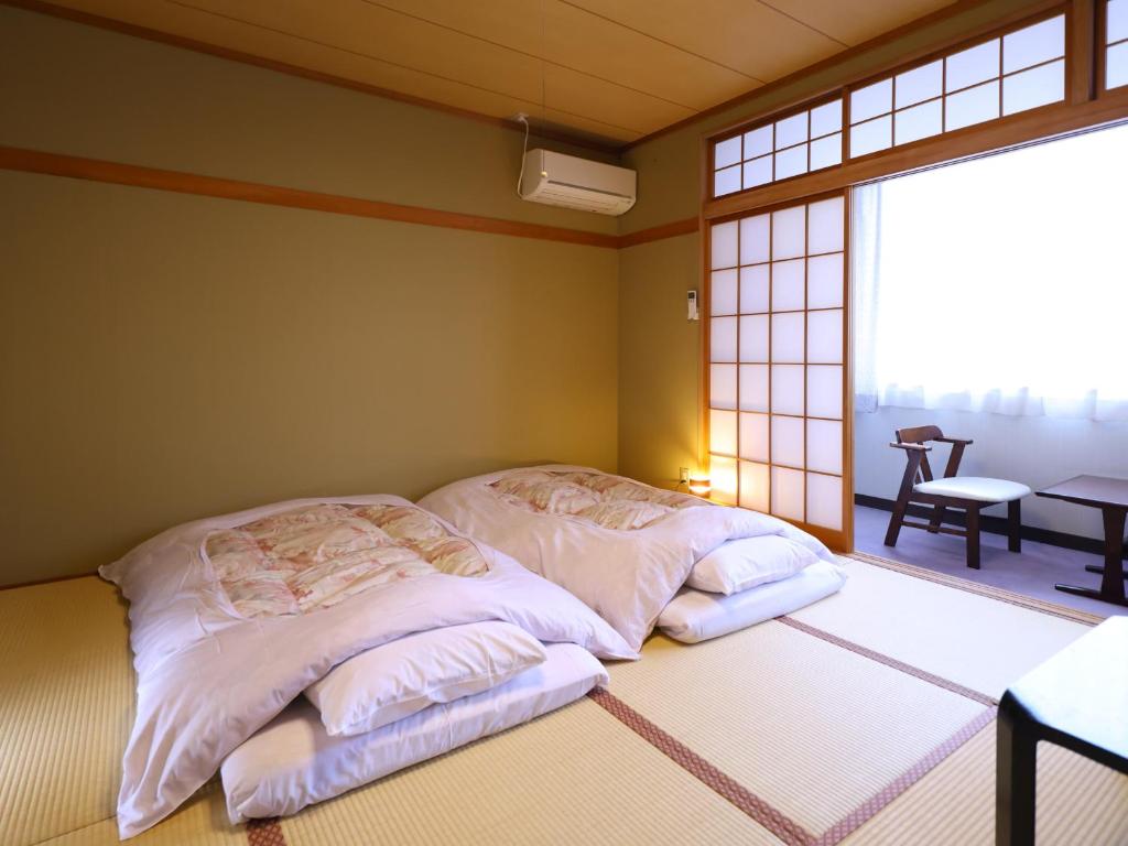 - une chambre avec 2 lits dans une chambre avec une fenêtre dans l'établissement 信州安曇野穂高温泉郷　旅館　山のたこ平, à Azumino