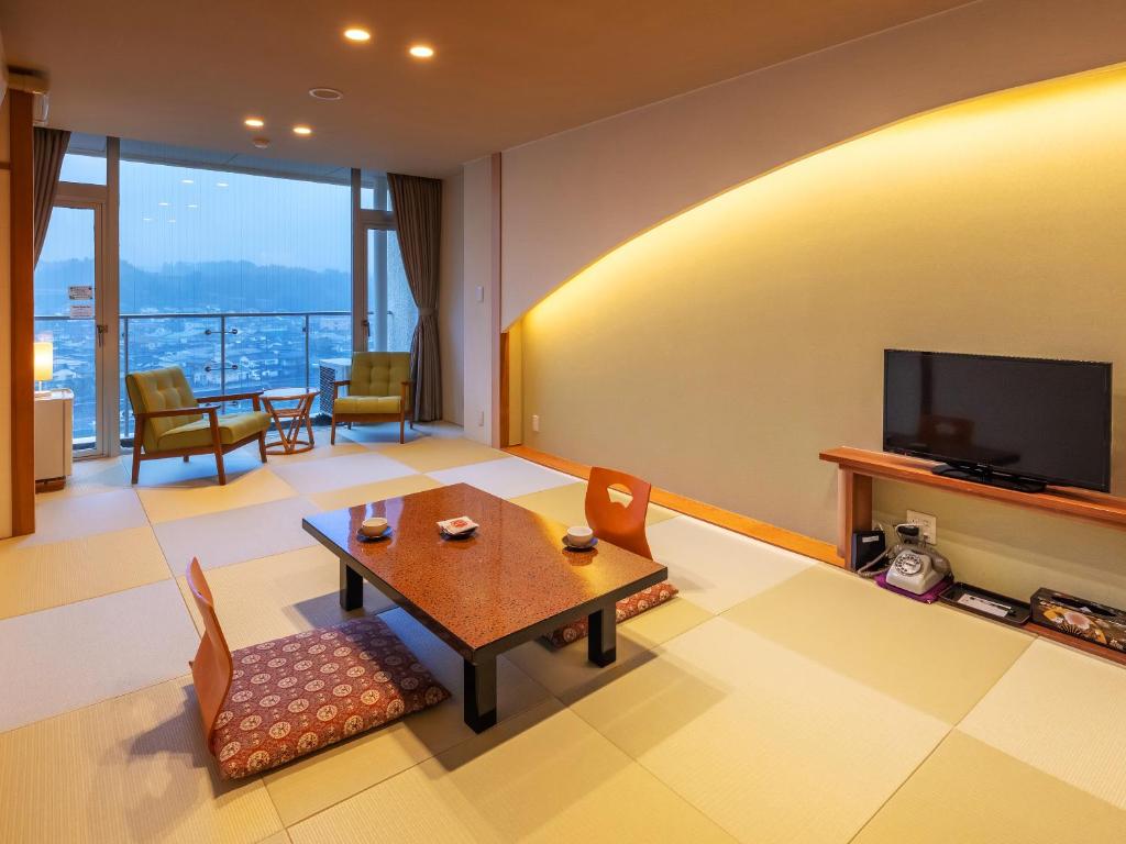 un salon avec une table et une télévision dans l'établissement Mikuma Hotel, à Hita