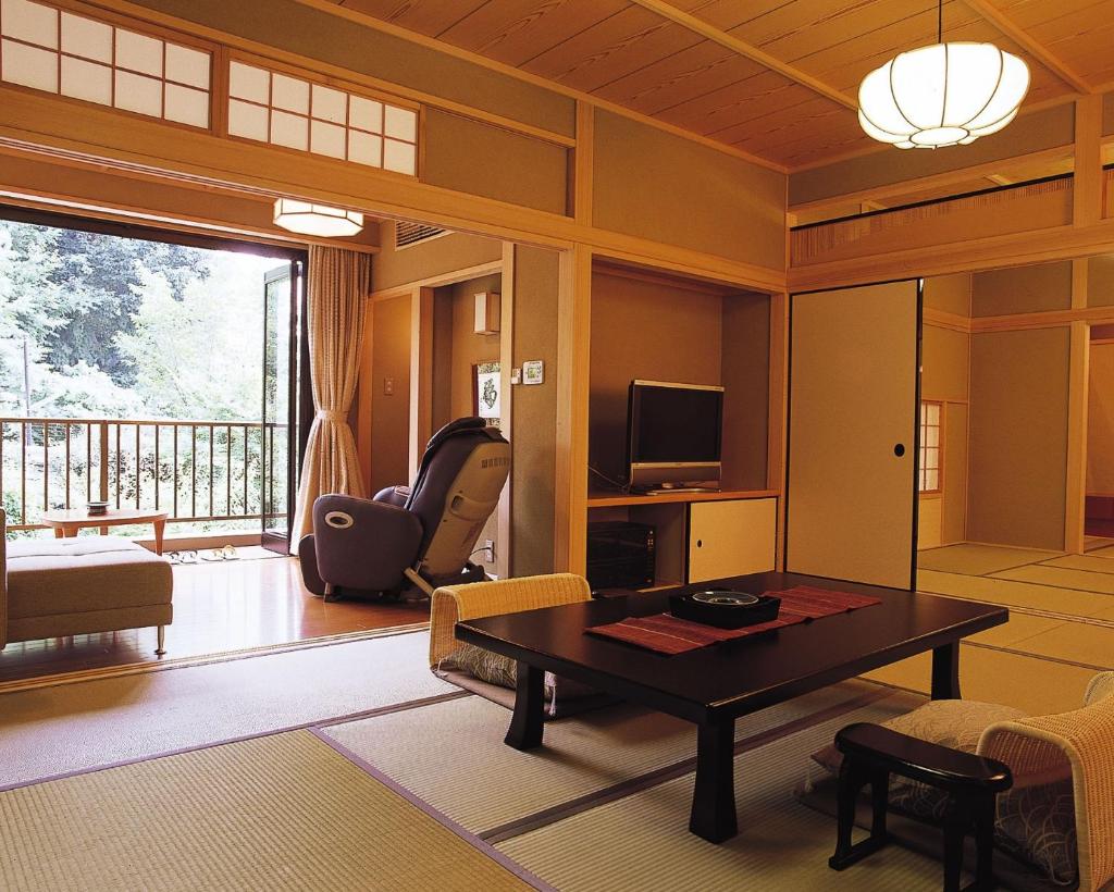 un salon avec une table et une télévision dans l'établissement Kasuga Hotel, à Nara