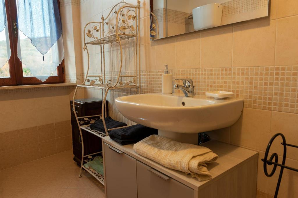 une salle de bain avec un lavabo et une étagère avec des serviettes dans l'établissement Appartamento Locazione Turistica L'Antica Sorgente Panicale, à Panicale