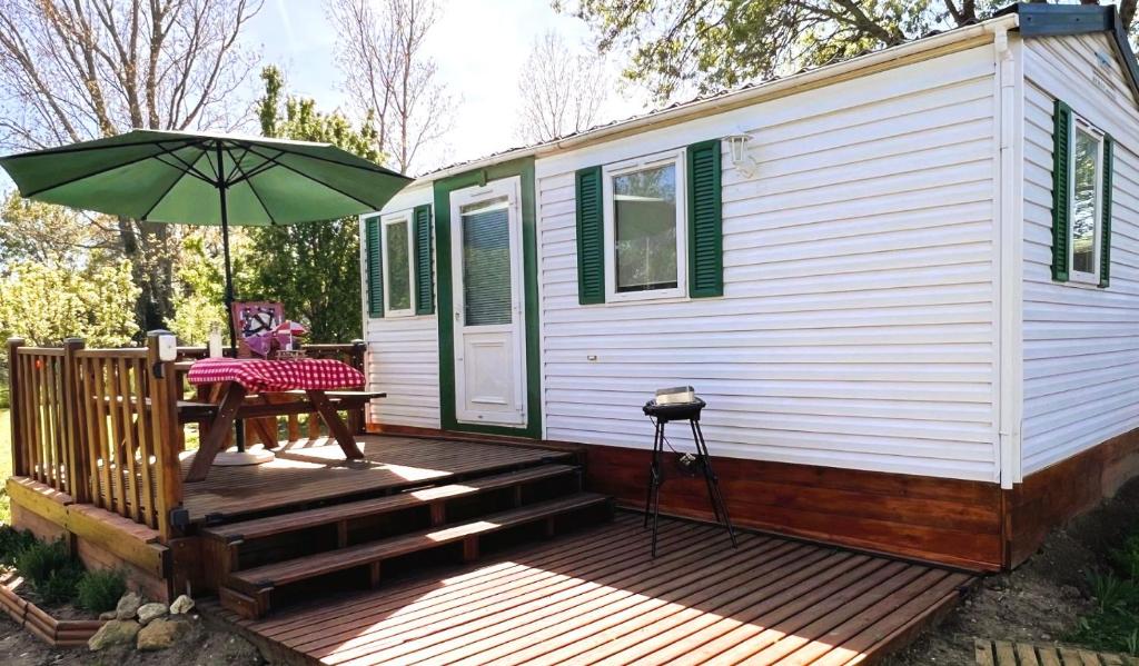 une petite maison avec une terrasse et un parasol dans l'établissement Cabane la Clef des Champs au Mas des Entrages, à Salon-de-Provence