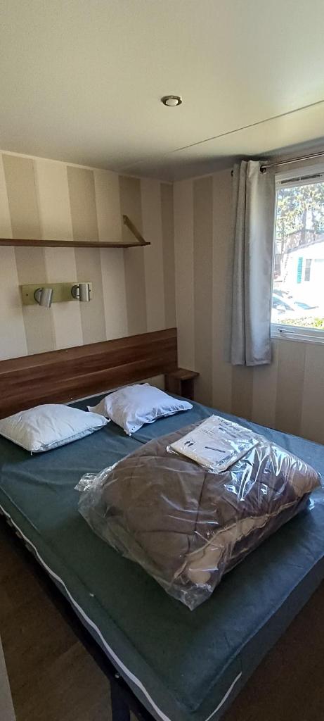 - une chambre avec un lit recouvert d'une housse dans l'établissement Mobil home 6 personnes confort Océan climatisé camping avec piscine Agde, à Agde