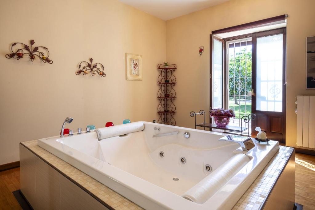 une grande baignoire blanche dans une salle de bain avec une fenêtre dans l'établissement Villa Alike - IsulaTravel, à Modica