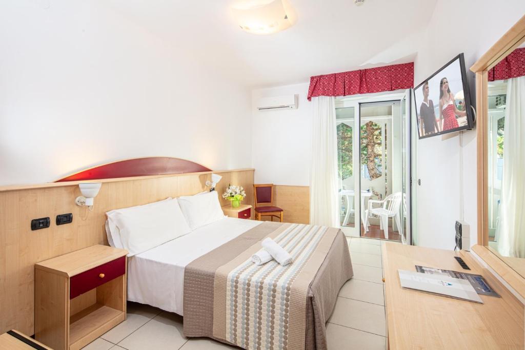 une chambre d'hôtel avec un lit et un bureau et une chambre dans l'établissement Hotel Regina, à Lignano Sabbiadoro