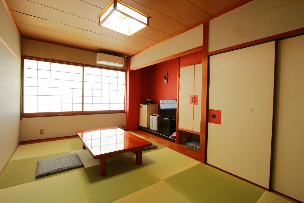 une chambre avec une table au milieu d'une pièce dans l'établissement 旅館　松乃湯, à Kutami