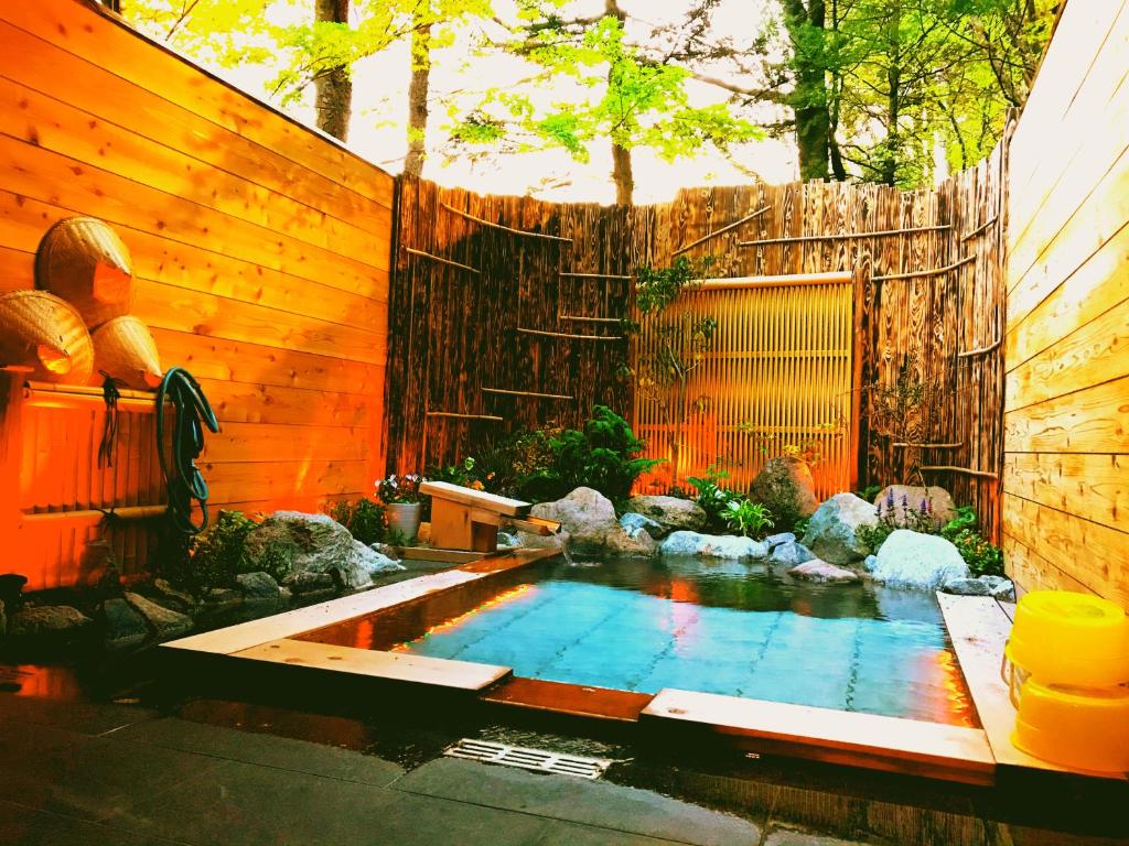 une piscine dans un jardin avec une clôture en bois dans l'établissement The TOJIBA 松川館, à Takayama