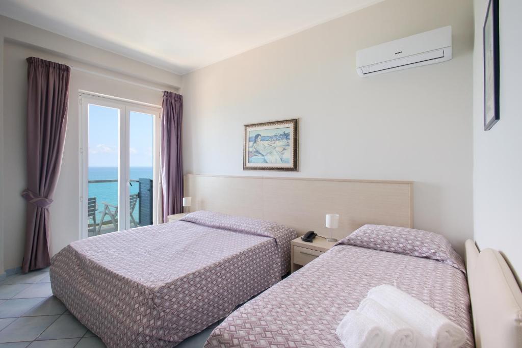 une chambre d'hôtel avec deux lits et un balcon dans l'établissement Hotel Tourist, à Cefalù