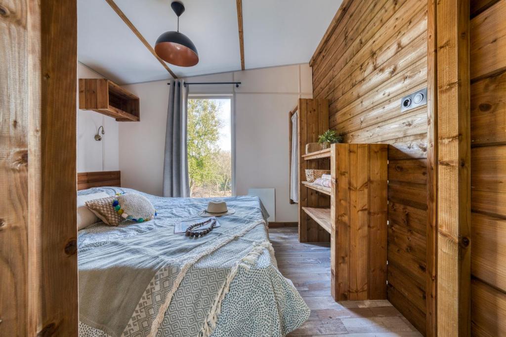 une chambre avec un lit et un mur en bois dans l'établissement Slow Village La Roque Sur Cèze, à La Roque-sur-Cèze