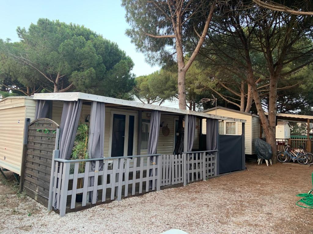 un mobile home avec une clôture blanche et des arbres dans l'établissement Camping pedro, au Grau-dʼAgde