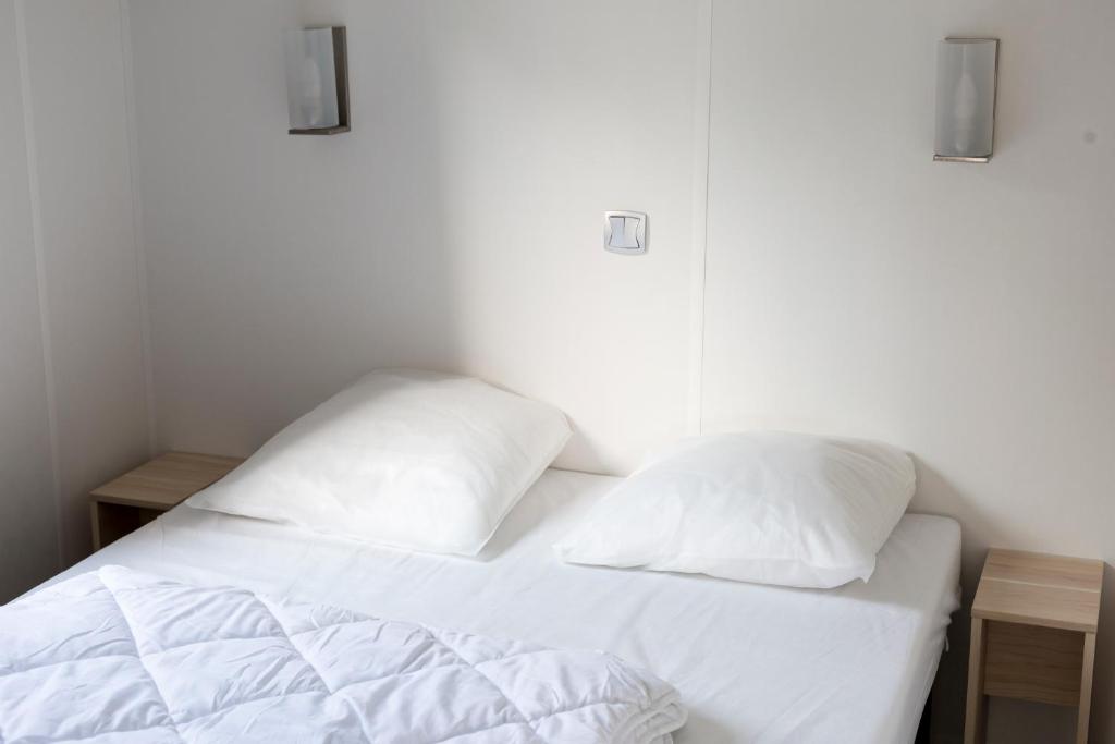 un lit blanc avec deux oreillers dessus dans l'établissement Camping touristique de Gien, à Poilly-lez-Gien