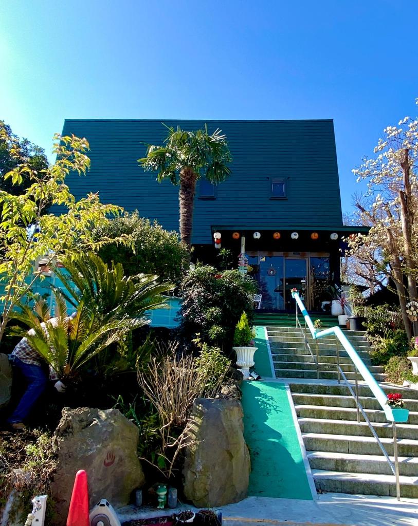 un bâtiment noir avec des escaliers et un palmier dans l'établissement Hanamizuki Onsen Resort, à Itō