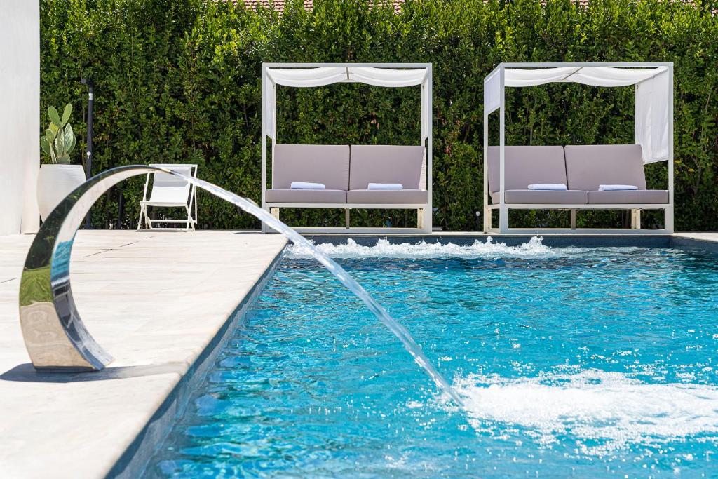 - une piscine avec une fontaine et 2 chaises dans l'établissement Villa Bonita, à Syracuse