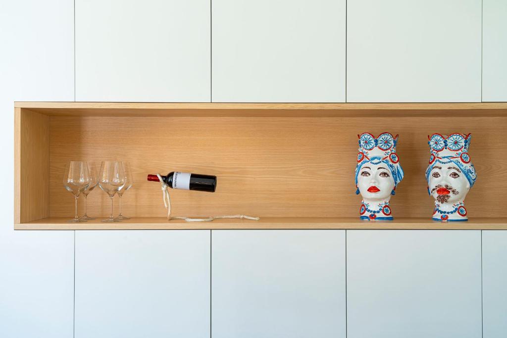 une étagère avec des verres à vin et deux masques de chiens dans l'établissement Villa Bonita, à Syracuse