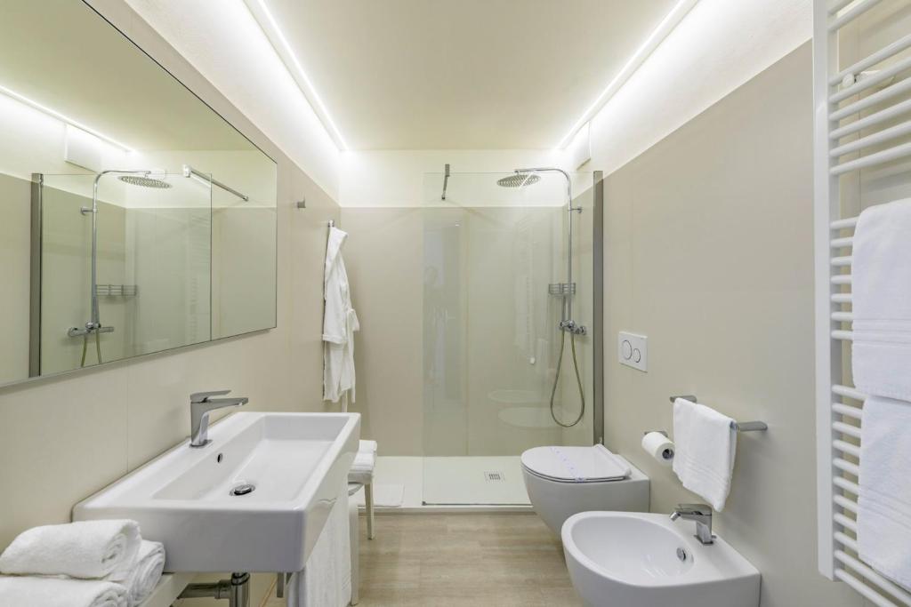 une salle de bain blanche avec un lavabo et des toilettes dans l'établissement Hotel Golf Inn, à Lignano Sabbiadoro