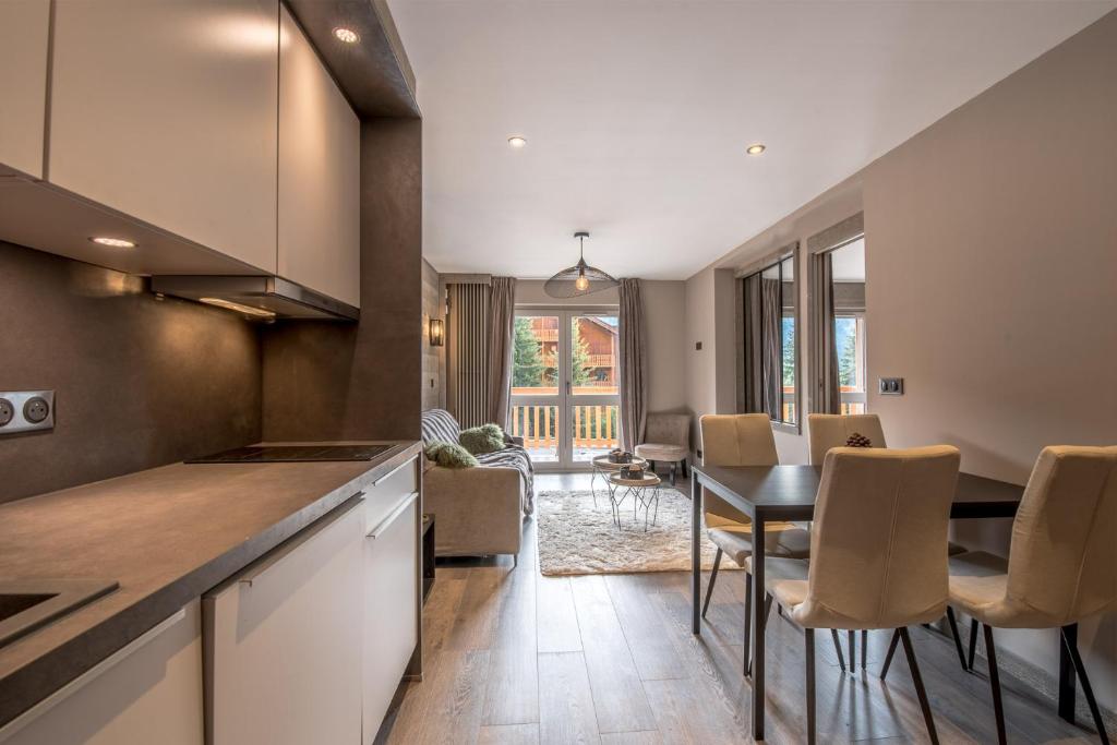 une cuisine et une salle à manger avec une table et des chaises dans l'établissement Superbe Appartement au Plateau Rond-Point des Pistes Classé 3 Etoiles et Label Méribel, à Les Allues