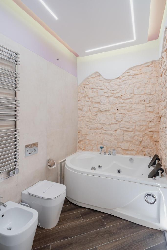une salle de bain avec une baignoire, des toilettes et un lavabo dans l'établissement LUXUITE Spa con Piscina o Jacuzzi, à Alberobello 82 autres photos