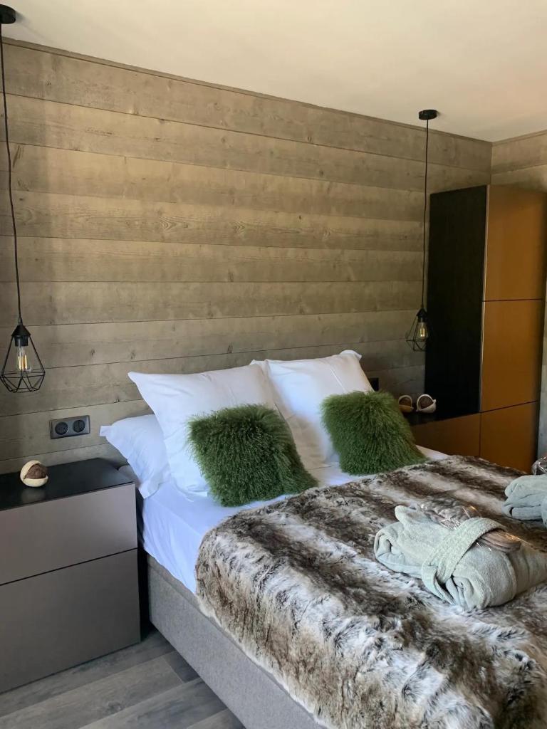 une chambre avec un lit avec des draps blancs et des oreillers verts dans l'établissement Superbe Appartement au Plateau Rond-Point des Pistes Classé 3 Etoiles et Label Méribel, à Les Allues