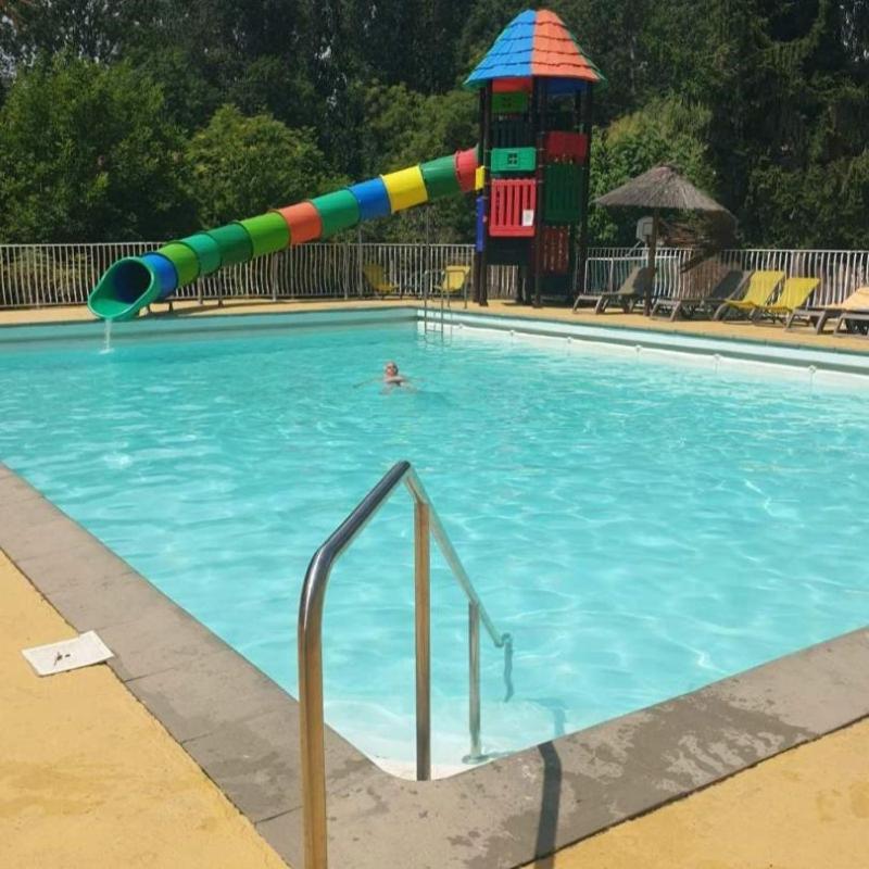 une personne dans une piscine avec toboggan dans l'établissement Camping Bois et Toilés, à Peyraud