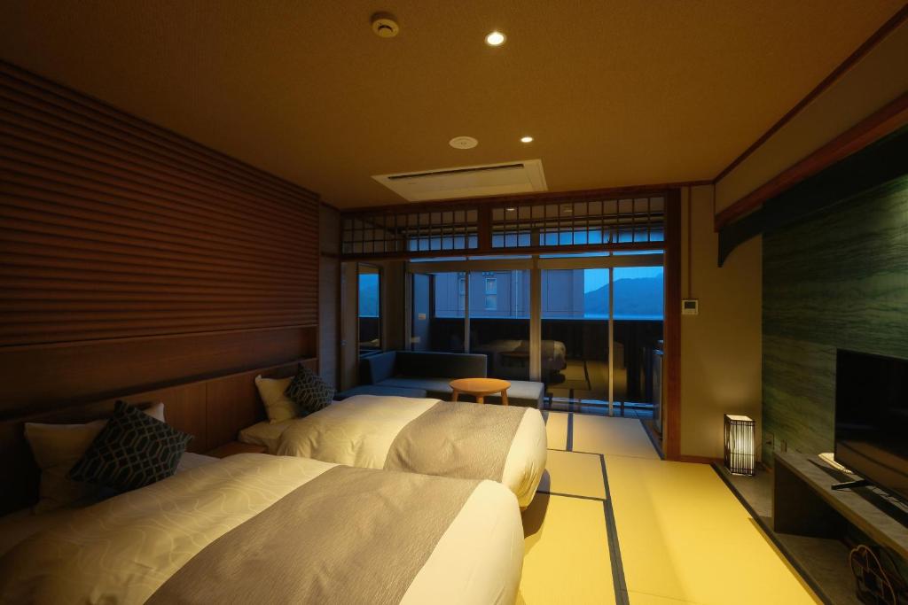 une chambre avec deux lits et une télévision à écran plat dans l'établissement Keishokan Sazanamitei, à Fukuyama