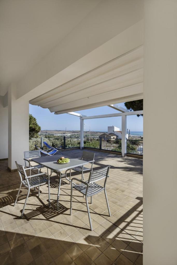 d'une terrasse avec une table et des chaises sous un auvent. dans l'établissement Sikelika Residence Sul Mare, à Scoglitti