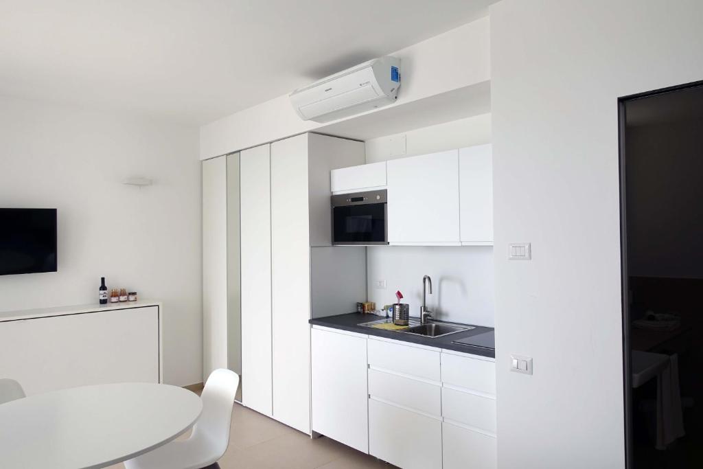 une cuisine avec des armoires blanches et une table blanche dans l'établissement Hotel e Residence Il Faro Acciaroli, à Acciaroli