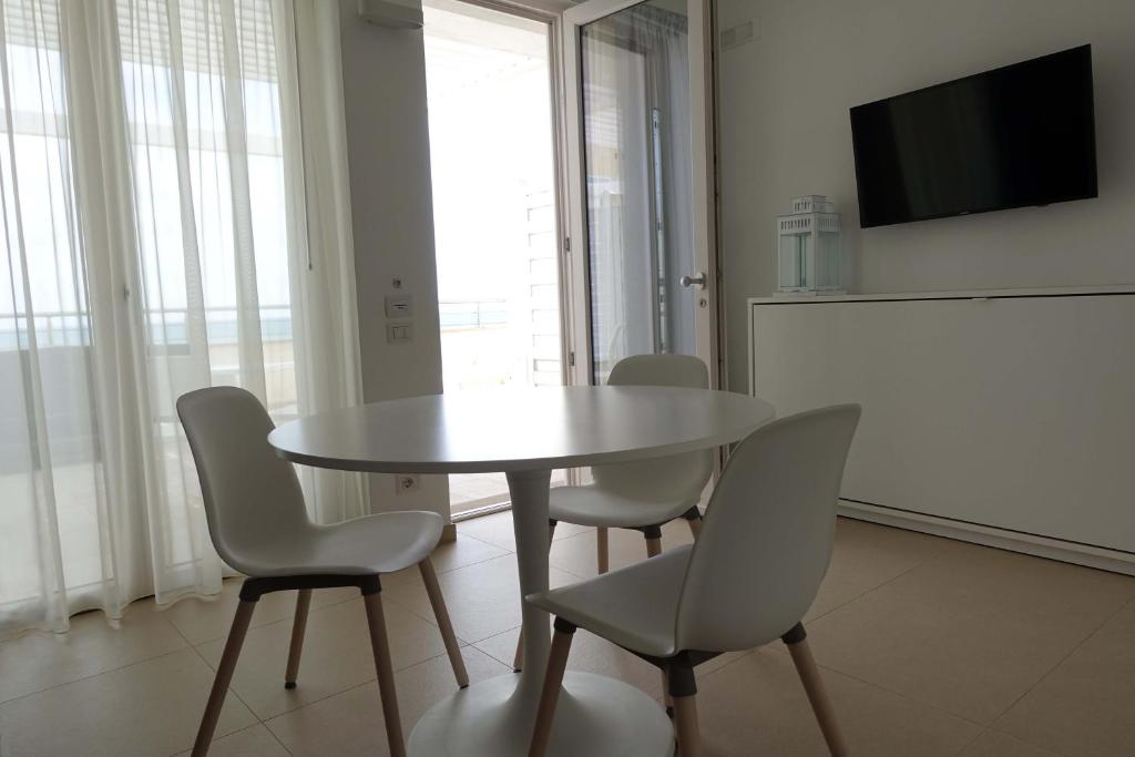 une salle à manger avec une table, des chaises et une télévision dans l'établissement Hotel e Residence Il Faro Acciaroli, à Acciaroli