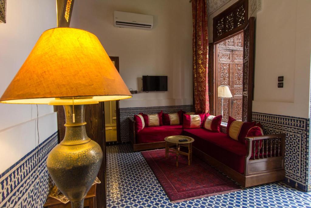 - un salon avec un canapé rouge et une lampe dans l'établissement Riad Al Makan Fes & Spa, à Fès